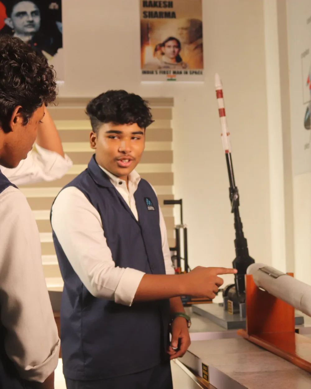 A student explaining how a model rocket works to a classmate