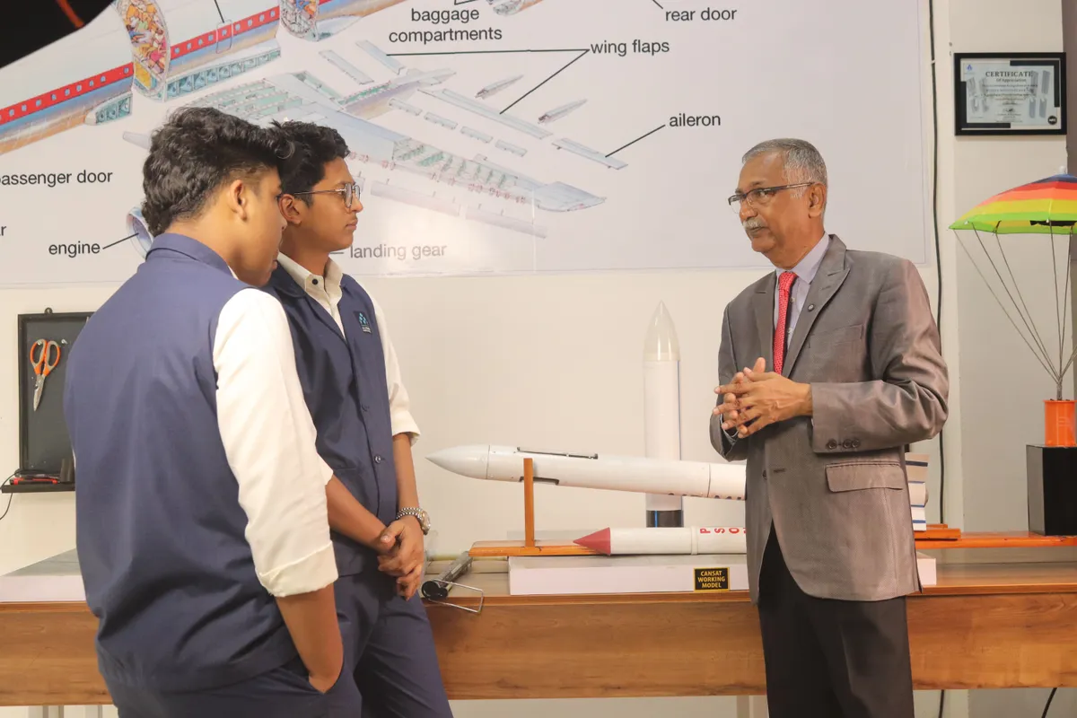 Dr. M.R.K. Menon explaining a rocket model to two students